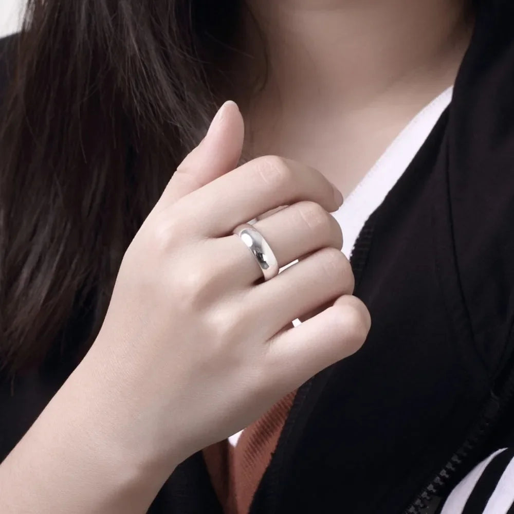 Close-up of a hand wearing a silver ring with a blurred background