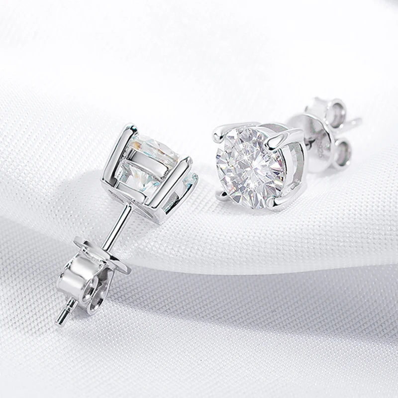 Pair of moissanite stud earrings on a white fabric background