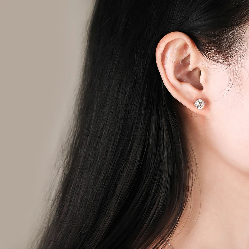 Close-up of an ear wearing a moissanite earring with long dark hair and a neutral background