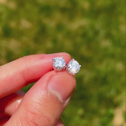 Video showcasing the glimmer of moissanite stones in stud earrings outside with a blurred grass background